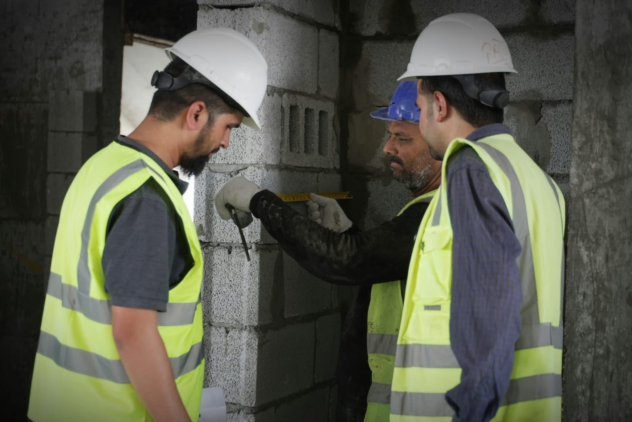 Engineers measuring a wall together, checking what is behind it before any work starts