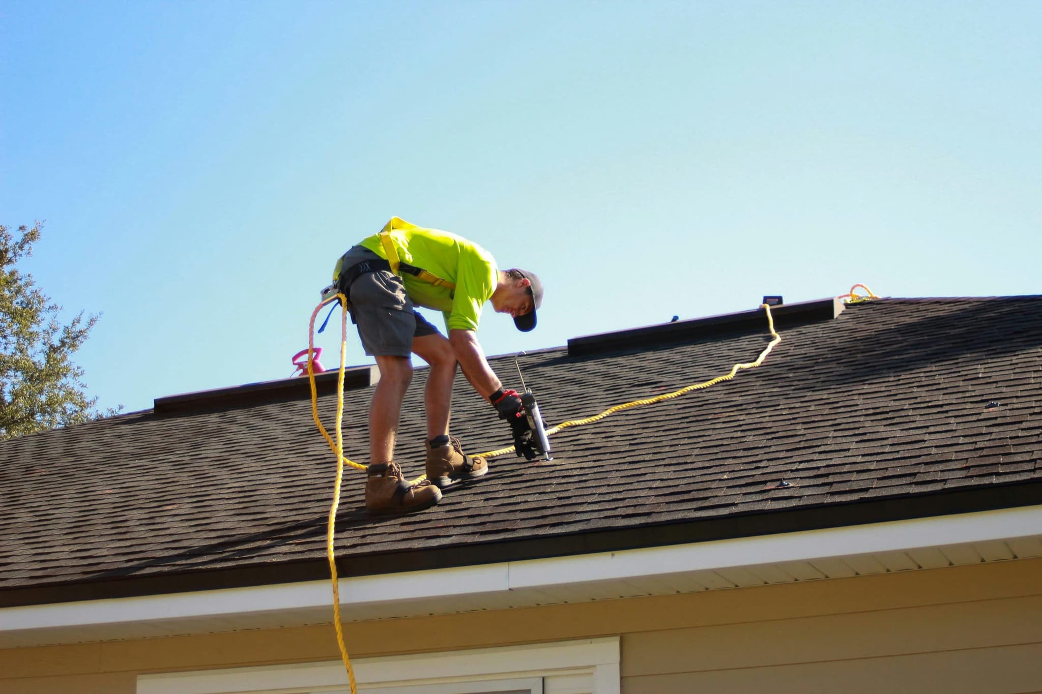 A technician working on a roof, harnessed and fixing equipment into place