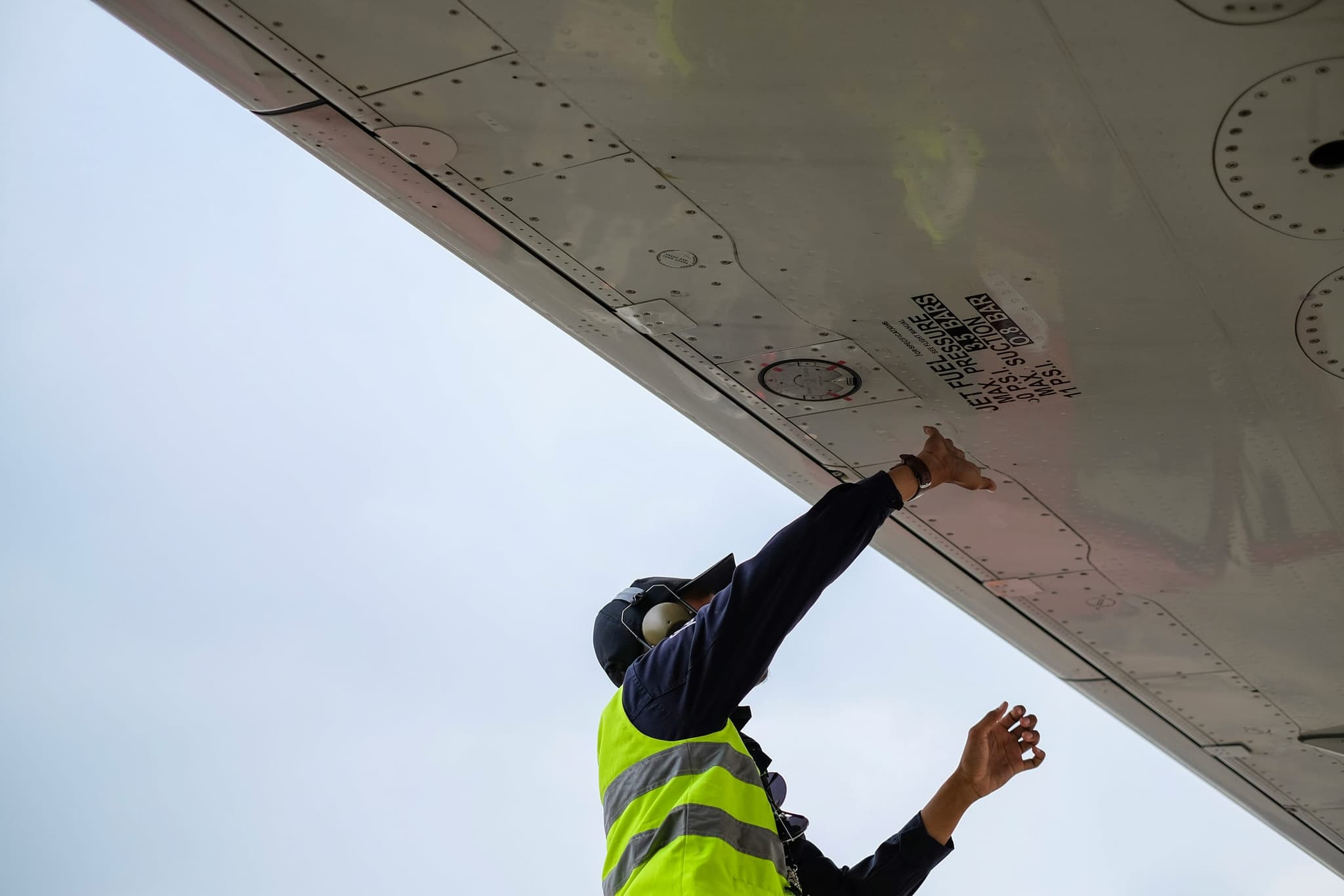 An engineer reaching up to check a fixing overhead during a routine inspection